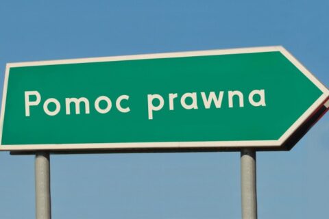 Drogowskaz zielony z białym napisem Pomoc prawna na tle nieba