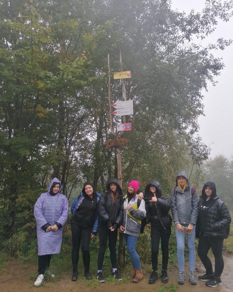 Uczennice stojące pod znakiem szlaku, na tle drzew