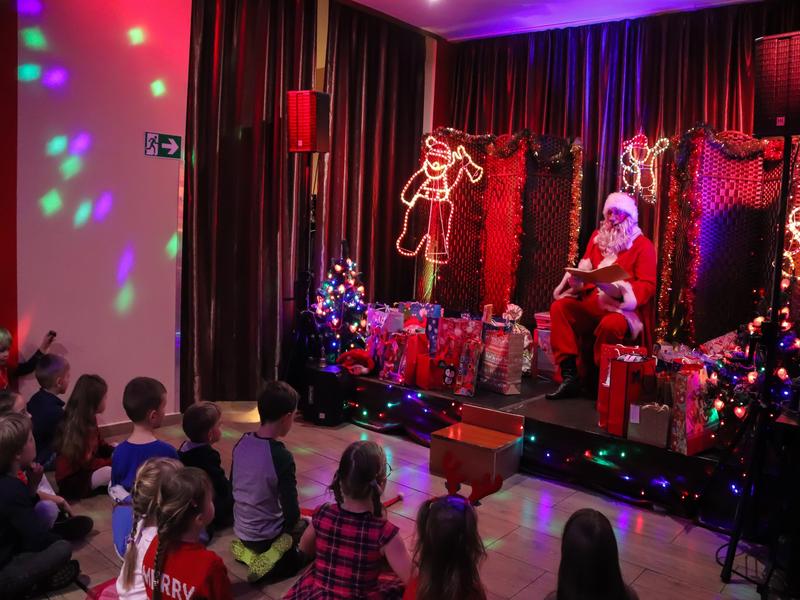 Spotkanie z Mikołajem w SCK - Jarzębina. Dzieci siedzą przed Mikołajem i czekają na prezenty