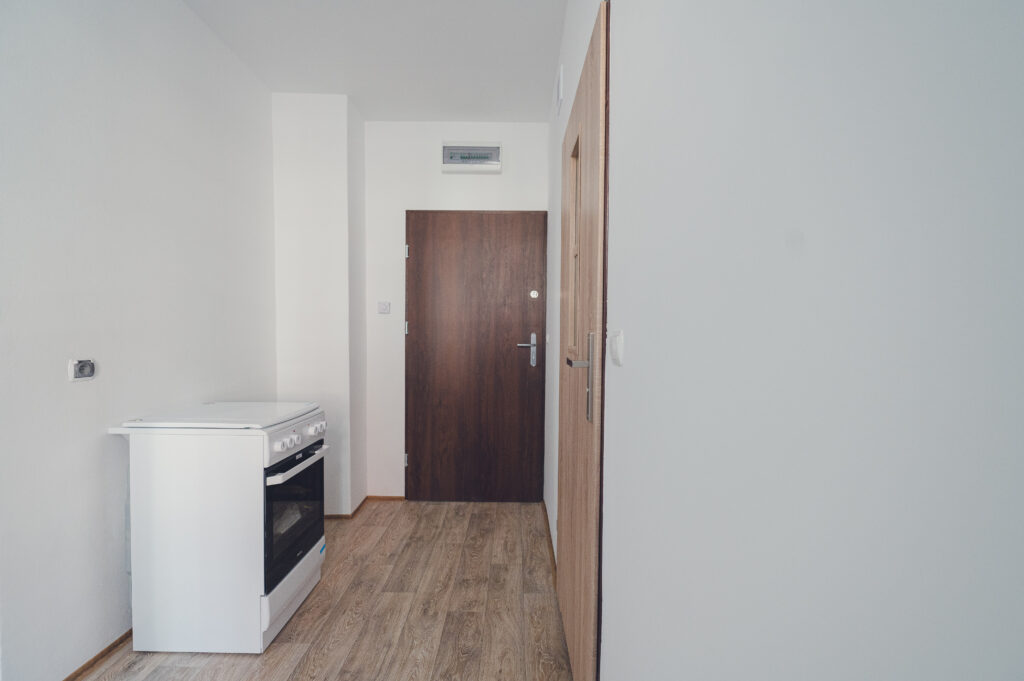 Wyremontowany lokal mieszkalny, na wprost drzwi, przy ścianie po lewej stronie stoi kuchenka