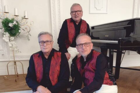 Trzech muzyków przy fortepianie w czarnych koszulach i bordowych kamizelkach