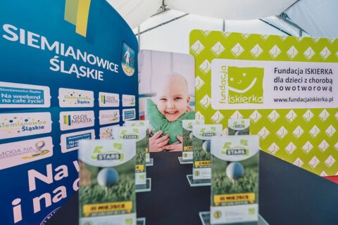 Charytatywny turniej golfowy 5 Stars Charity Cup. Na zdjęciu plakat z dzieckiem oraz nagrody.