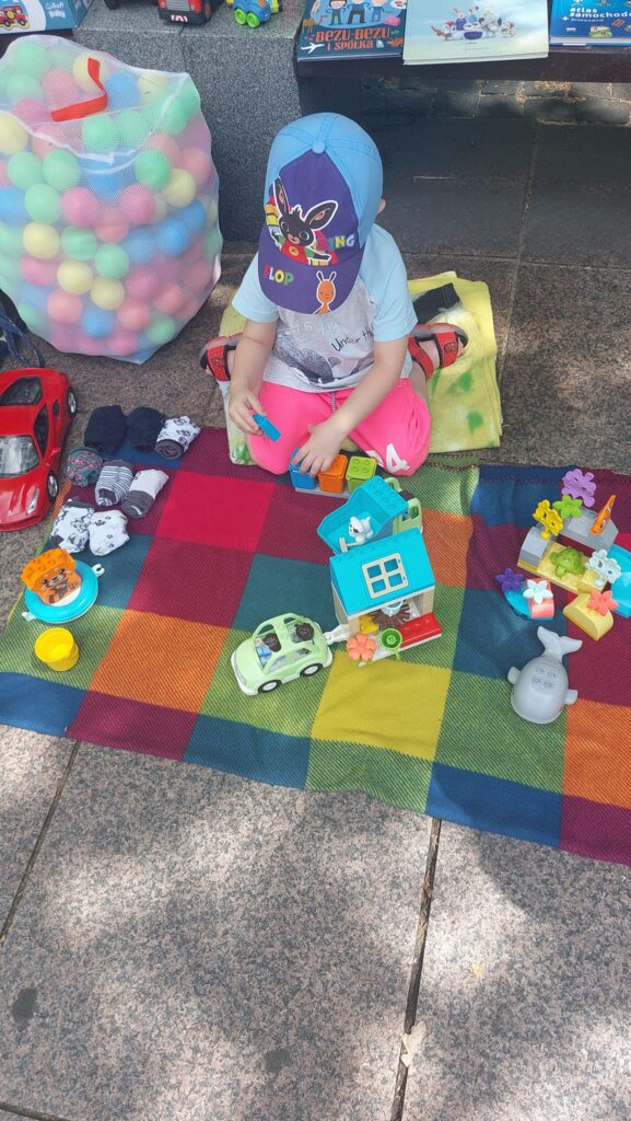 Dziecko z zabawkami podczas wyprzedaży garazowej