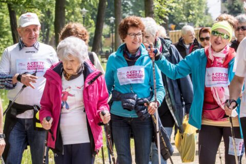 Seniorzy w trakcie spaceru z kijkami nordic walking.