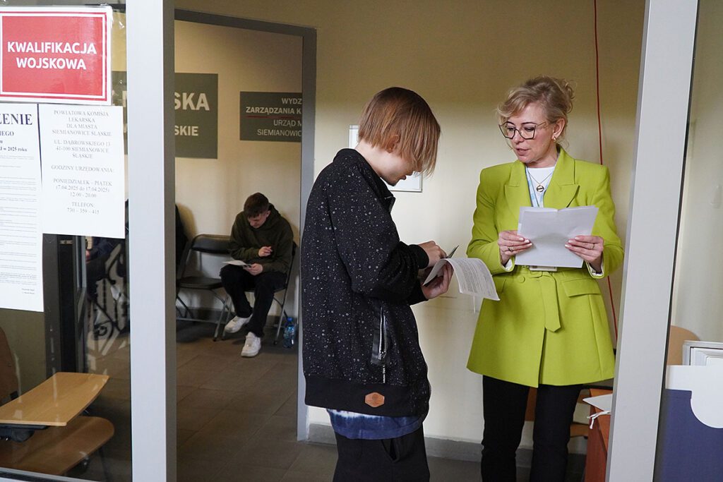 Izabela Pesel, Zastępca Naczelnika Wydziału Zarządzania Kryzysowego przyjmuje dokumenty od wezwanych młodych mężczyzn.