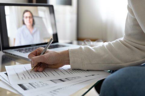 Szkolenie online przed ekranem laptopa. Na stoliku rozłożone dokumenty.