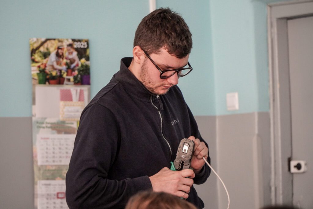 Przedstawiciel MMJ pokazuje uczniom montaż wtyczki na przewodzie sieciowym.