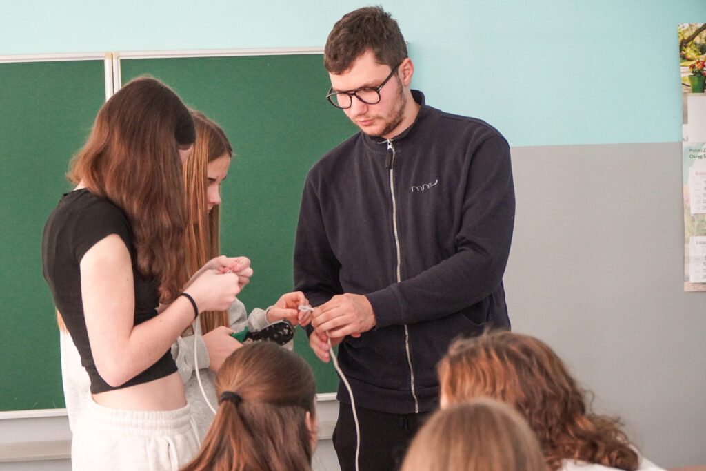 Przedstawiciel firmy MMJ demonstruje uczniom zakładanie wtyczki RJ na przewodzie sieciowym podczas zajęć praktycznych.
