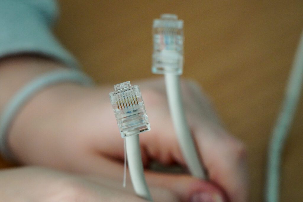 Dwie wtyczki RJ widoczne na końcach przewodów sieciowych przygotowanych przez uczniów.