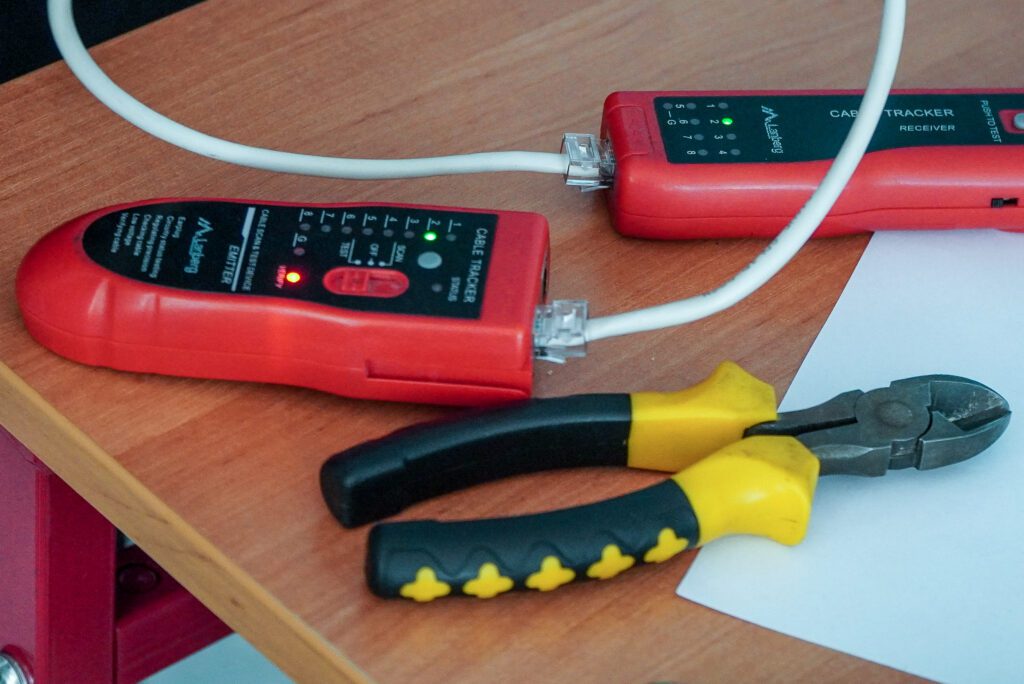 Tester kabli sieciowych oraz cęgi leżące na stole podczas praktycznych zajęć Akademii Przedsiębiorczości.