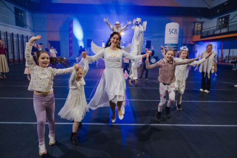 Dzieci i dorosła w przebraniu anioła skaczą wspólnie w kole podczas finału Heaven Wins.