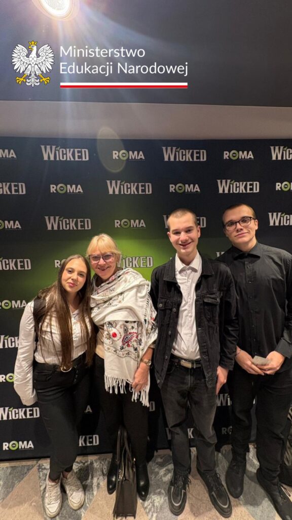 Uczniowie wraz z nauczycielem na ściance Teatru Roma