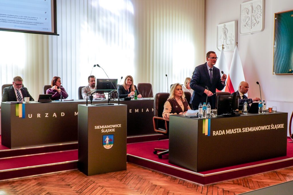 Przewodniczący Rady Miasta przemawia przy stole prezydialnym. Obok siedzą członkowie prezydium Rady Miasta.