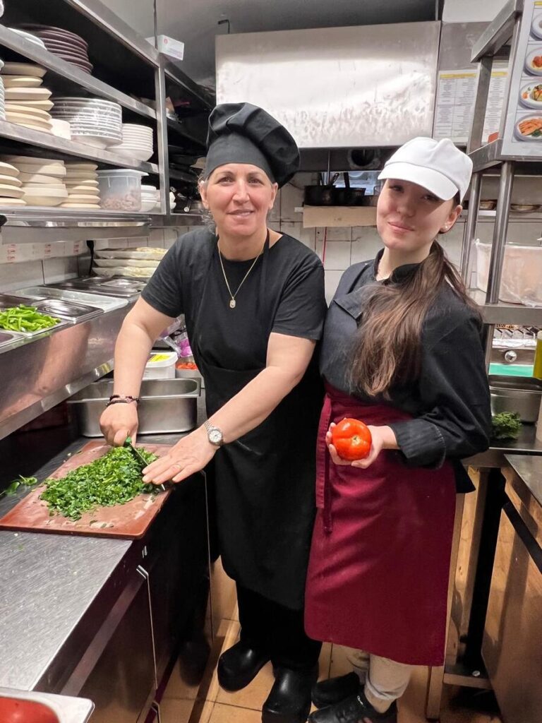 Uczennica ZS Cogito kroi warzywa z szefową kuchni.