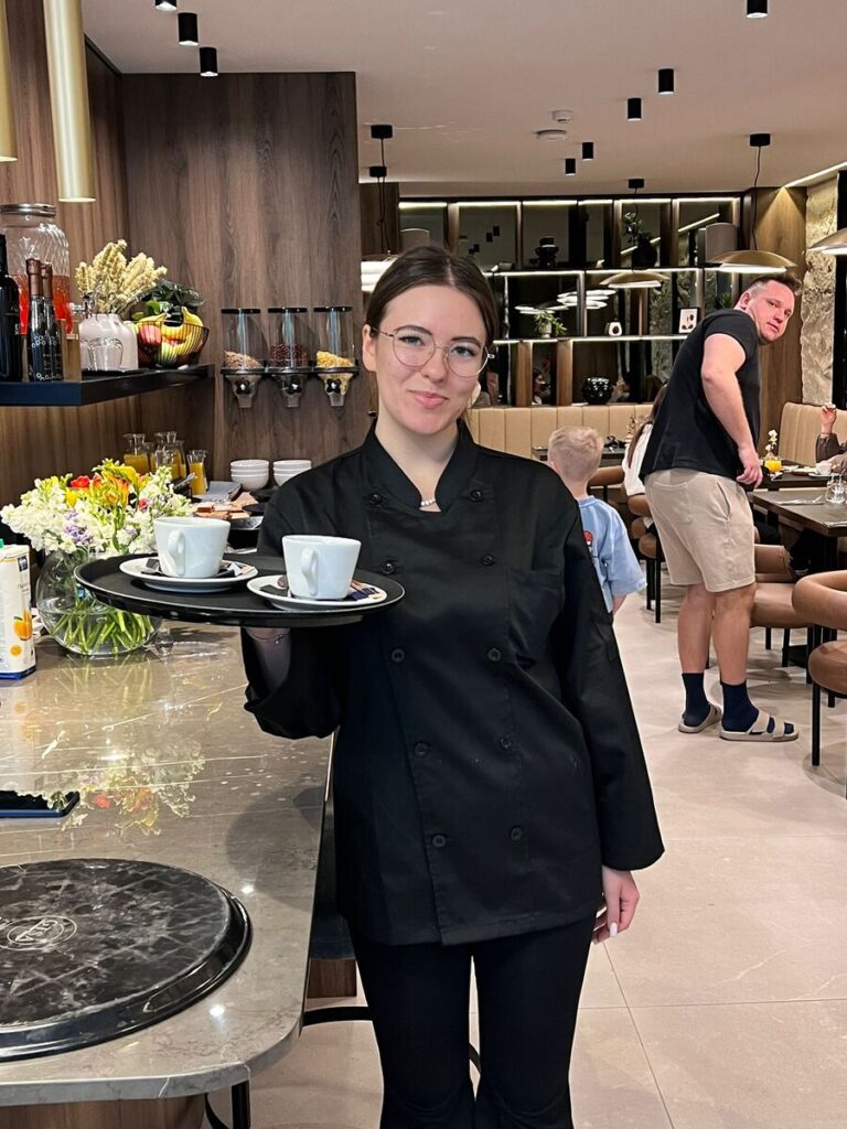 Uczennica ZS Cogito obsługuje gości z tacą.