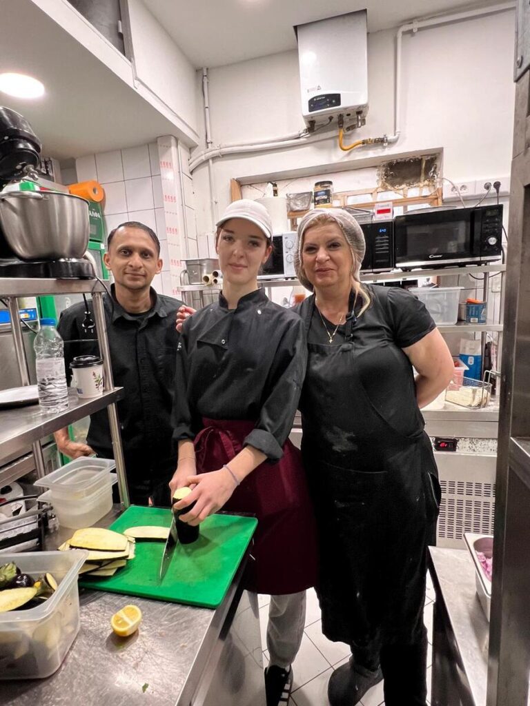 Uczennica ZS Cogito z szefami restauracji w czasie krojenia bakłażana.