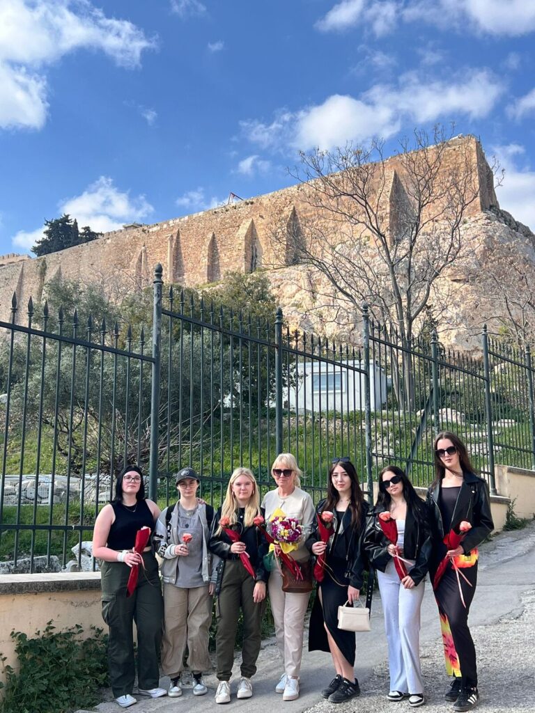 Uczennice i nauczycielka z kwiatami w tle Akropol