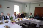Beata Gałecka, Drugi Zastępca Prezydenta Miasta (biała marynarka) w trakcie spotkania wielkanocnego w Śląskim Stowarzyszeniu Charytatywnym "Przystań". Ludzie siedzą za stolikami nakrytymi białym obrusem.