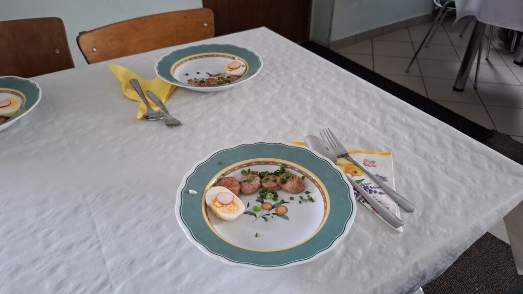 Talerzyki z wielkanocnym jajkiem na stoliku z białym odświętnym obrusem.