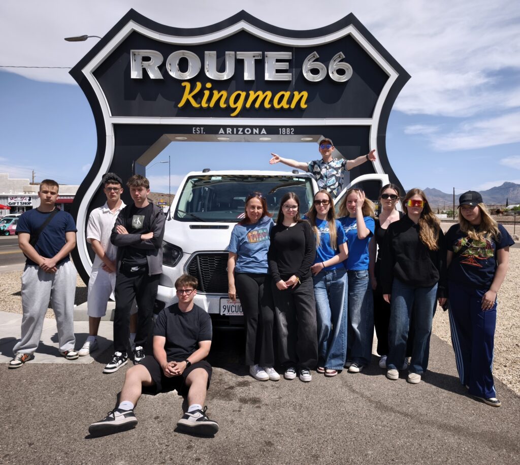 Zdjęcie grupy młodzieży przy kultowym znaku legendarnej amerykańskiej drogi Route 66.