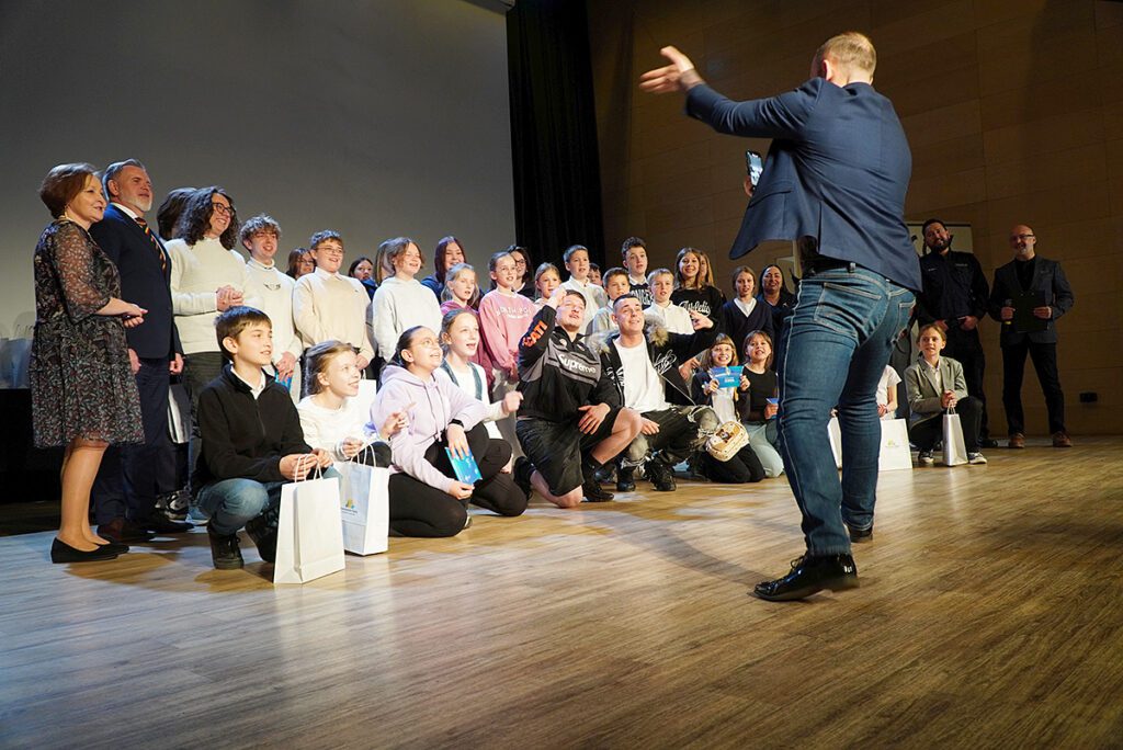 Krzysztof Drabik dynamicznie ustawia laureatów konkursu do pamiątkowego zdjęcia.