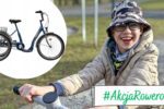 RPo prawej uśmiechnięty chłopiec w okularach i kapeluszu siedzi na rowerze na tle parku. Po lewej widoczny rower rehabilitacyjny trójkołowy. Na dole napis „#AkcjaRowerowa”.