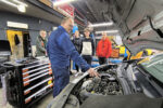 Mechanik pokazuje uczniom co znajduje się w silniku auta.