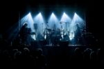Na scenie SCK - Bytków troje muzyków zespołu SBB gra na klawiszach, perkusji i gitarze. Oświetleni są jasnymi reflektorami scenicznymi, przed sceną w półmroku siedzi publiczność.