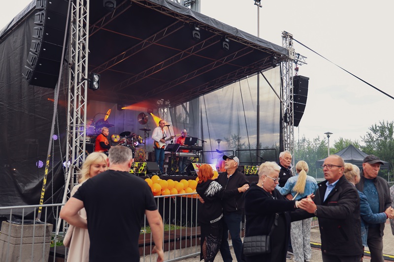 Uczestnicy bawią się i tańczą podczas plenerowej potańcówki przy muzyce zespołu występującego na scenie pod szybem dawnej kopalni.