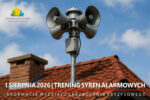 Metalowy maszt z czterema głośnikami syren alarmowych umieszczony na dachu budynku pokrytego czerwoną dachówką. Na dole grafiki widoczny biały napis na czerwonym tle zapowiadający trening syren.