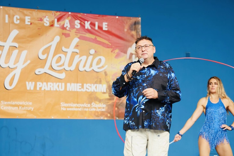 Wesoły Masorz na scenie podczas koncertu w Amfiteatrze Miejskim, a obok artystka prezentuje pokaz z szarfą.