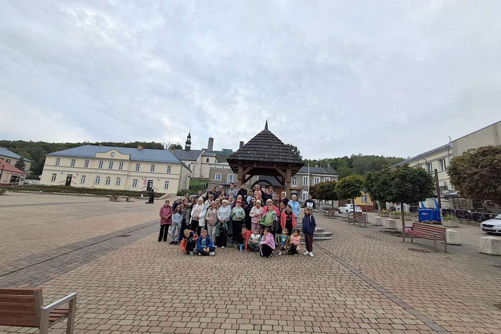 Rodziny zastępcze wraz z dziećmi podczas wspólnego zdjęcia na rynku w Chęcinach.