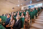 Grupa siemianowickich nauczycieli siedzi na zielonych fotelach sali widowiskowej Siemianowickiego Centrum Kultury Park Tradycji.